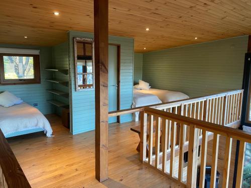 a room with two beds and a staircase in a house at Lofts Magnolias in Puerto Varas