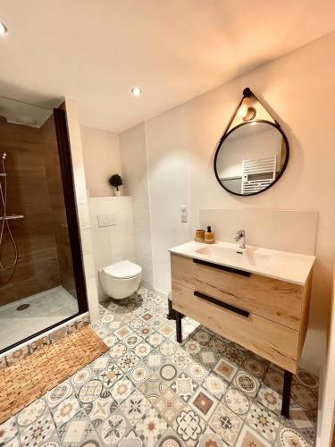 a bathroom with a sink and a toilet and a mirror at La Petite Maison in Villargondran