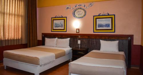two beds in a hotel room with a clock on the wall at Hotel Benedicta in Mexico City