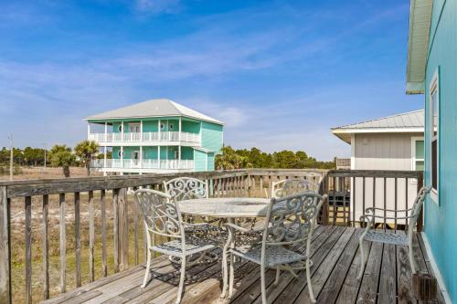 een tafel en stoelen op een terras met een huis bij Breaking Even in Gulf Shores