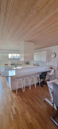 a large kitchen with a large white counter and chairs at Holiday home close to forest, lake and skiing in Ulricehamn