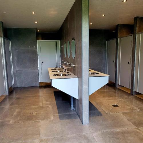 a large bathroom with three sinks and stalls at Simpel overnachten in Langeveen