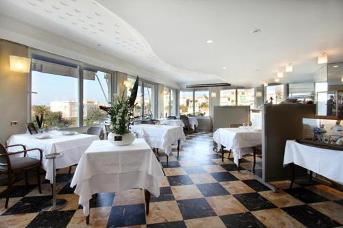 a restaurant with white tables and chairs and windows at Le Rhul in Marseille