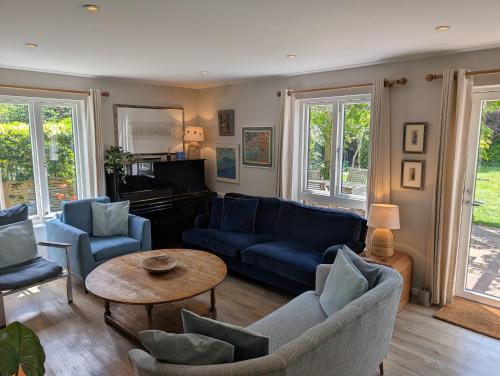 a living room with blue couches and a table at Lewes Heights is a spacious modern luxury home with stunning views in Lewes