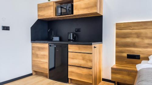 a small kitchen with a black counter and wooden cabinets at apartmány Svätého Martina in Holíč