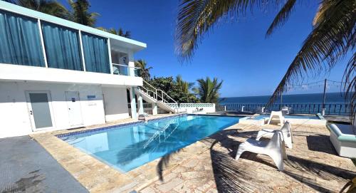 a house with a swimming pool next to the ocean at Ventana Va104 at Arecibo 681 Ocean Drive in Arecibo