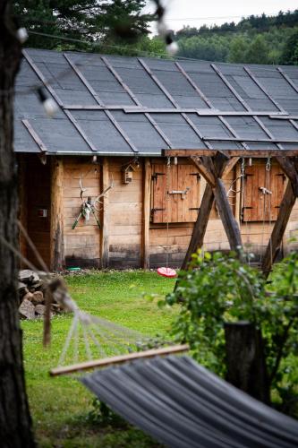 a hammock in front of a house with a solar roof at Myśliwska chata Staś i Nel in Bystrzyca Kłodzka