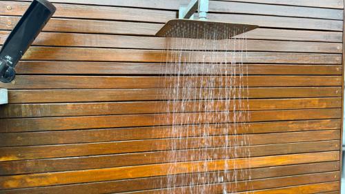 a hose is spraying water on a wooden wall at Casa de Praia a 150m da praia com Conforto Total Ar-Condicionado, Enxoval, Wi fi e Piscina Privativa in Peruíbe