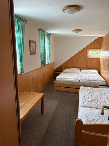 a room with two beds and a table in it at Chata VISTA Strážné in Strážné