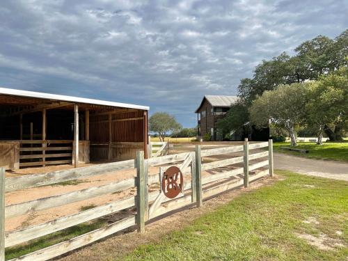 a wooden fence next to a barn with a sign on it at Private cabin on 100 scenic acres with balcony views in Pipe Creek