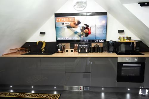 a kitchen with a counter with a tv on the wall at Castle Queen in Coseley