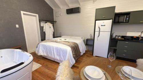 a room with a bed and a kitchen with a refrigerator at Vila Chamonix - Chalé Carmenere in Urubici