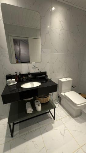 a bathroom with a sink and a toilet and a mirror at Vila Chamonix - Chalé Carmenere in Urubici