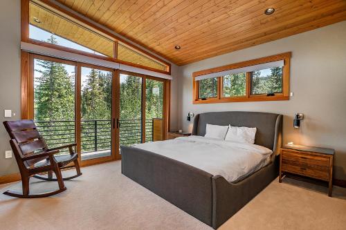 Un dormitorio con una cama y una silla y ventanas. en Luxury Ski Chalet - 684 Vasquez Road, en Winter Park