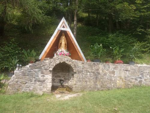 a stone fireplace with a triangular roof on a stone wall at Dvojizbový Útulný Apartmán Oščadnica in Oščadnica