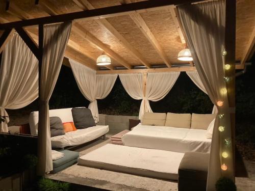 acovered patio with a couch and chairs under a roof at Csudahely - WonderPlace in Dunabogdány