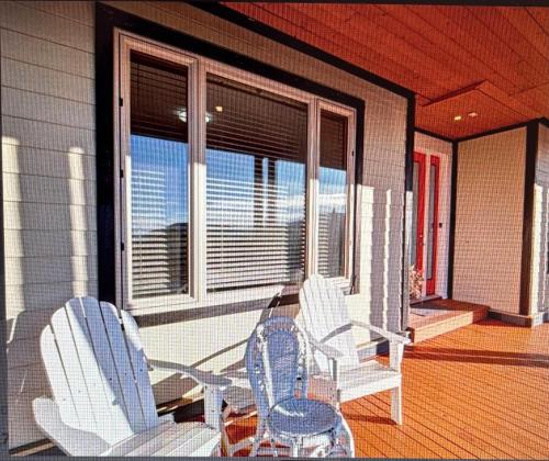 two chairs and a table on the porch of a house at Beaches Downtown Suite In Sechelt in Sechelt