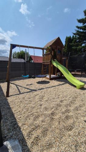 a playground with a green slide in a yard at Chalupa u rybára s Wellness a detským ihriskom in Liptovský Trnovec