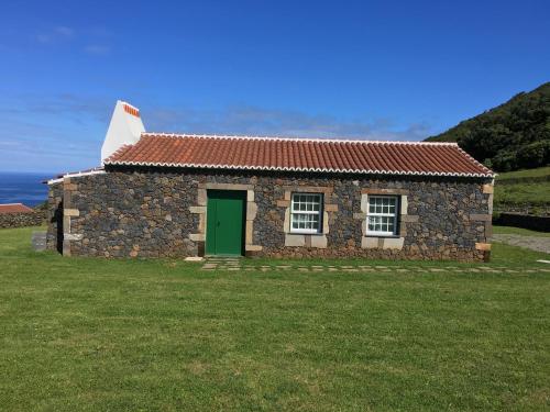 a stone house with a green door on a grass field at Pico da Vigia in Santa Bárbara