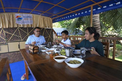 a group of people sitting at a table eating food at Riveria Caravan Houseboat in Champakulam