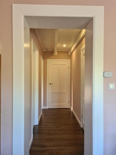 an empty hallway with a white door and wood floors at B&B het Zandoogje in Hollandscheveld