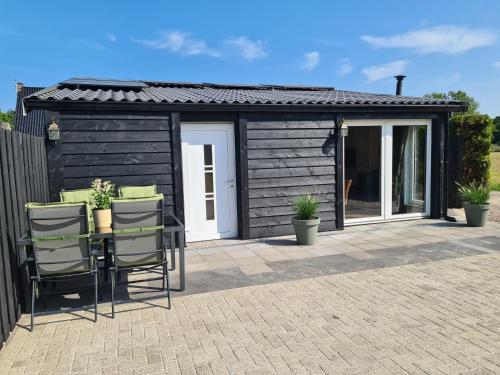 a black shed with chairs on a patio at B&B het Zandoogje in Hollandscheveld