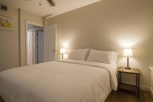 a bedroom with a large white bed with two lamps at 2BR w King Bed Pool Steps to Forest Park CWE in Tower Grove
