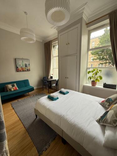 Un dormitorio con una gran cama blanca y una ventana. en Charming studio flat in vibrant Leith, en Edimburgo