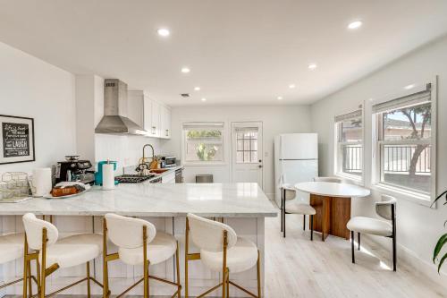 a kitchen with a large white counter and chairs at 7 Mi Huntington Beach Family Home with Patio! in Midway City