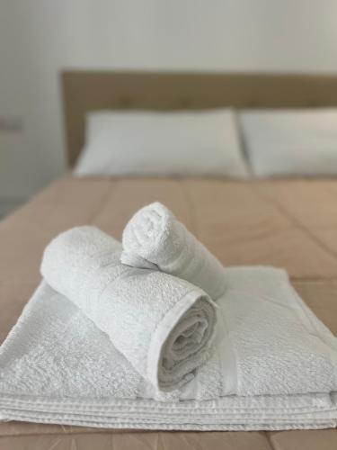 a stack of white towels on a bed at R&S Apartment in Monza