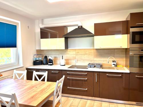 a kitchen with brown cabinets and a wooden table at Apartament Luna in Gryfice