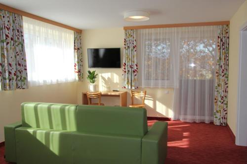 a living room with a green couch and a television at Gasthof Martinhof in Sankt Martin im Sulmtal