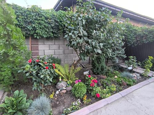 un giardino con fiori e piante accanto a un muro di Комфортный дом до 4х человек. Есть парковка на 2 машины, Wi-Fi, TV. a Bishkek