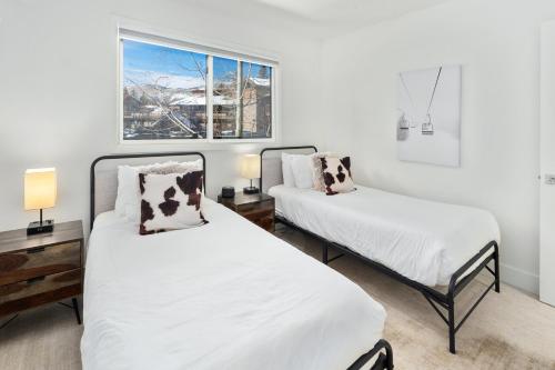 two beds in a room with white walls and a window at Crestwood 3213 Premier 2 Bedroom Grand in Snowmass Village