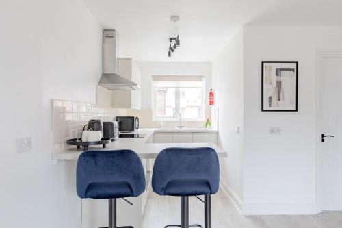 a kitchen with two blue chairs and a counter at West London - Easy London Underground Access in Hounslow