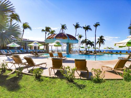eine Gruppe von Stühlen und Sonnenschirmen neben einem Pool in der Unterkunft Pierre Mundo Imperial Riviera Diamante Acapulco in Acapulco