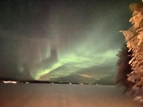 an aurora in the sky over the water at night at Lumossa Aurora Lakeside House in Rovaniemi
