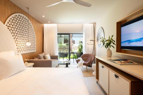 a bedroom with a living room with a television at Mitsis Rodos Village in Kiotari