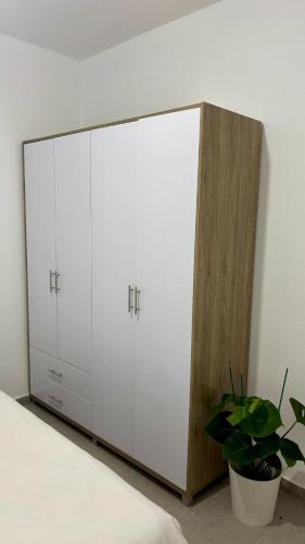 a bedroom with two white cabinets and a potted plant at Beach Suite Israel, Beachfront Suite, Indoor Pool, Gym Spa ביץ סוייט ישראל בריכה מקורה, חדר כושר וספא בבניין in Ashqelon