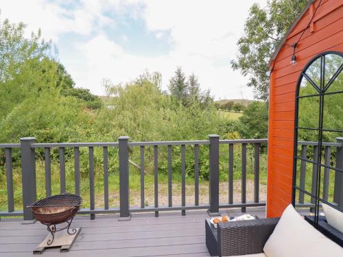 a grill on a deck with a fence at Red Kite at Wild Valley Huts in Oswestry