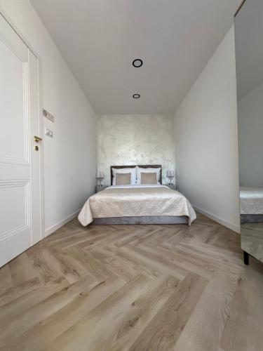 a bedroom with a bed and a wooden floor at Apartament EROS II in Bolesławiec