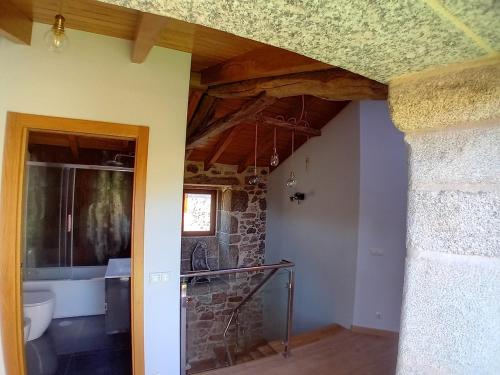 Un baño con lavabo y pared de piedra. en A Casa da Ponte, en Negreira