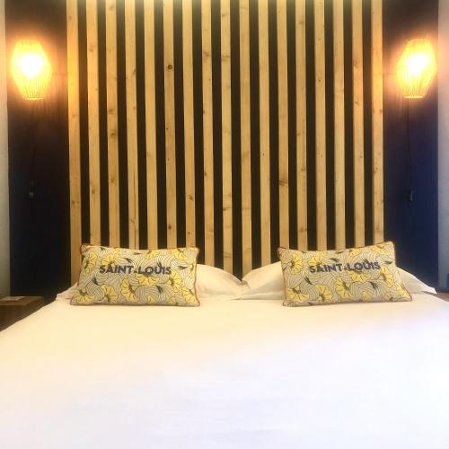 a bed with two pillows on top of it at Hôtel Jas Neuf in Sainte-Maxime