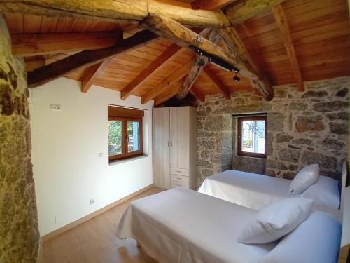 Un dormitorio con dos camas y una pared de piedra. en A Casa da Ponte, en Negreira