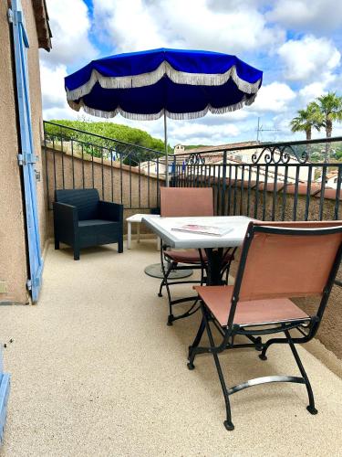 a table and chairs on a balcony with an umbrella at Hôtel Jas Neuf in Sainte-Maxime