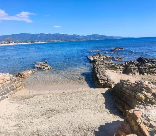 a beach with rocks and the ocean on a sunny day at Perdas Room in Quartu Sant'Elena