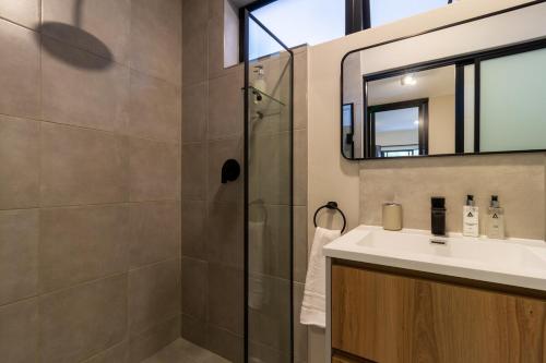 a bathroom with a shower and a sink and a mirror at #AlimamaSpaces The Rob's Akaru in Johannesburg