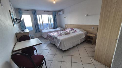 a bedroom with two beds and a table and chairs at Hotel Kolman in Capão da Canoa