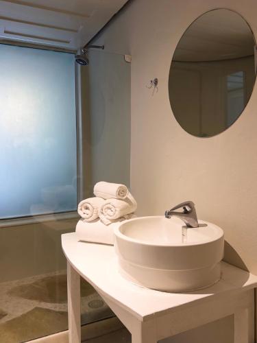 a bathroom with a sink and a mirror and towels at Own Búzios Beach Hotel in Búzios