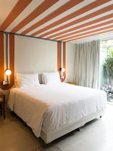 a bedroom with a large white bed in front of a window at Own Búzios Beach Hotel in Búzios